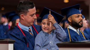 Graduate holding a young child