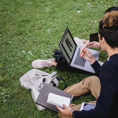 Students sitting on the grass of the Campus Mall working on an assignment together