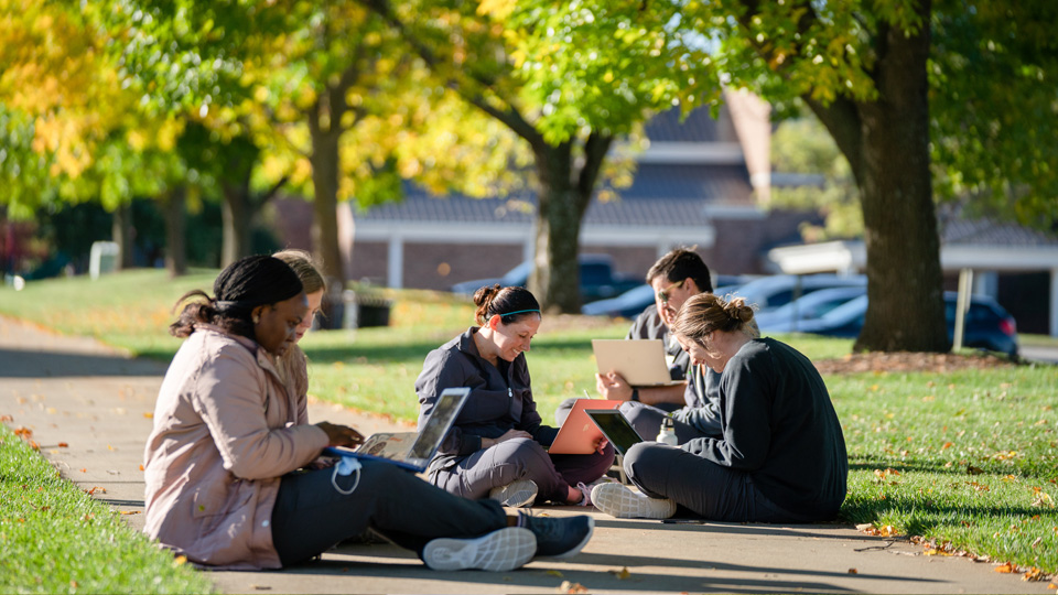 Students sitting on the sidewalk on the Campus Mall