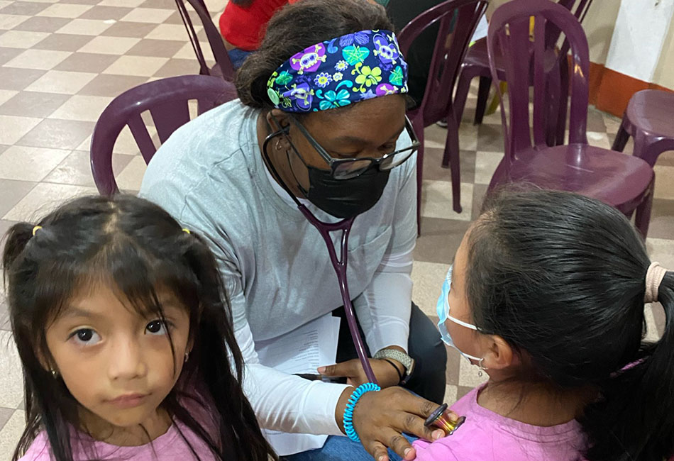 nursing student doing health assessment with two children in the clinic