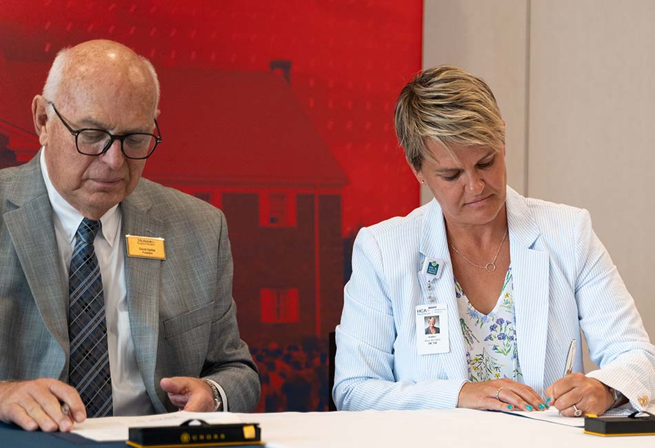 Dr. David Spittal, MNU President and Amber Boes, Chief Nursing Officer, HCA Midwest Health, sign a partnership agreement