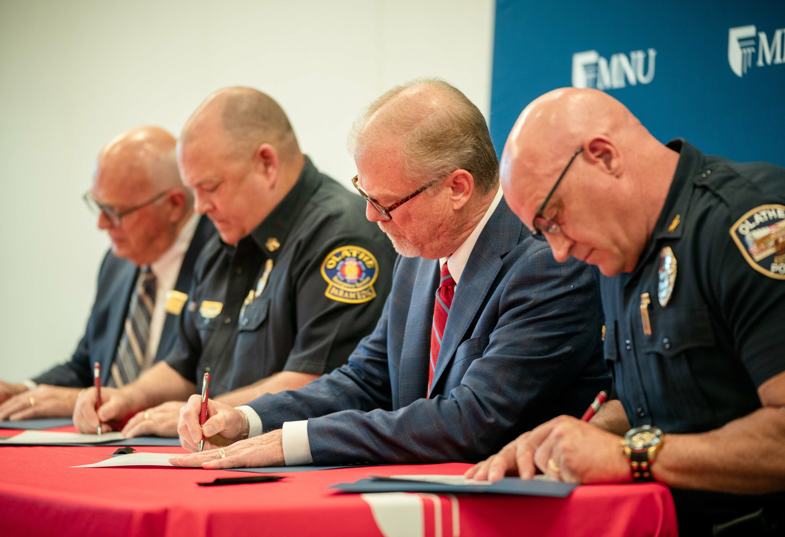 MNU President David Spittal, Fire Chief Jeff DeGraffenreid, Mayor John Bacon and Police Chief Mike Butaud signing scholarship agreement