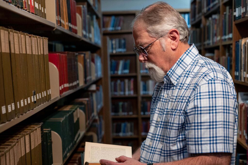 Lon Dagley examines a rare book from the 1800s in the Marge Smith Archives at MNU.