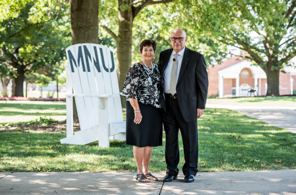 Donna and David Spittal by the MNU Welcome Home chair on the MNU campus mall, Aug 2020