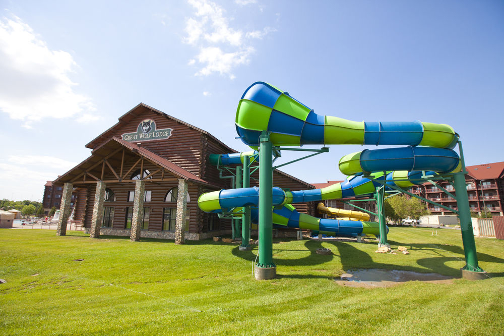 Image of the outside of the Great Wolf Lodge on sunny day, featuring the log cabin exterior and a waterslide