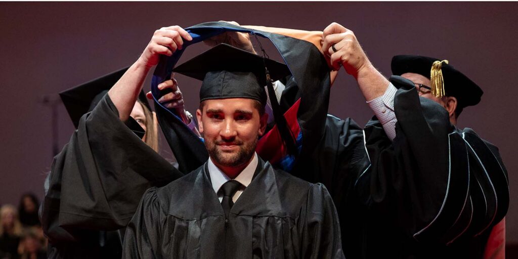 Trey Larimer being hooded for his master's degree