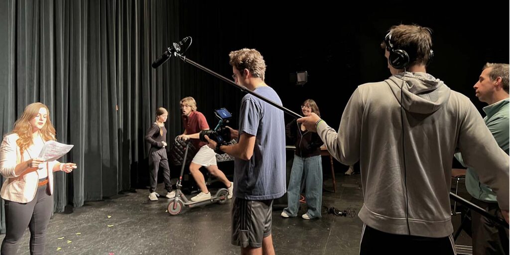 Actors and students filming a scene.