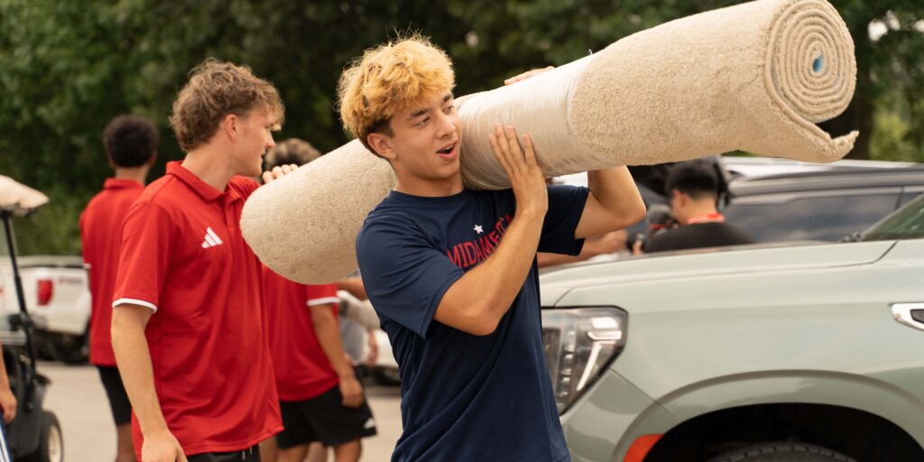 Male student carrying carpet into dorm