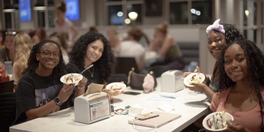 4 female students enjoying ice cream in dining hall